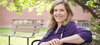 Une femme fournisseur de soins de santé est assise à l'extérieur sur le terrain d'un hôpital.