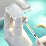 Hand holding syringe and vial