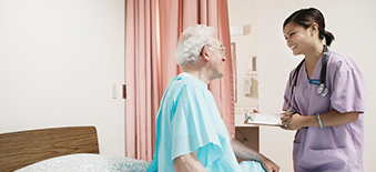 Technicienne tenant dans ses mains une radiographie au chevet d'un patient âgé. 