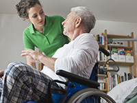 Patient in a wheelchair gets assistance from her health care professional