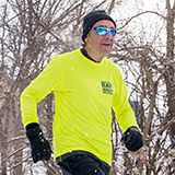 man running outdoors through a forest in the winter